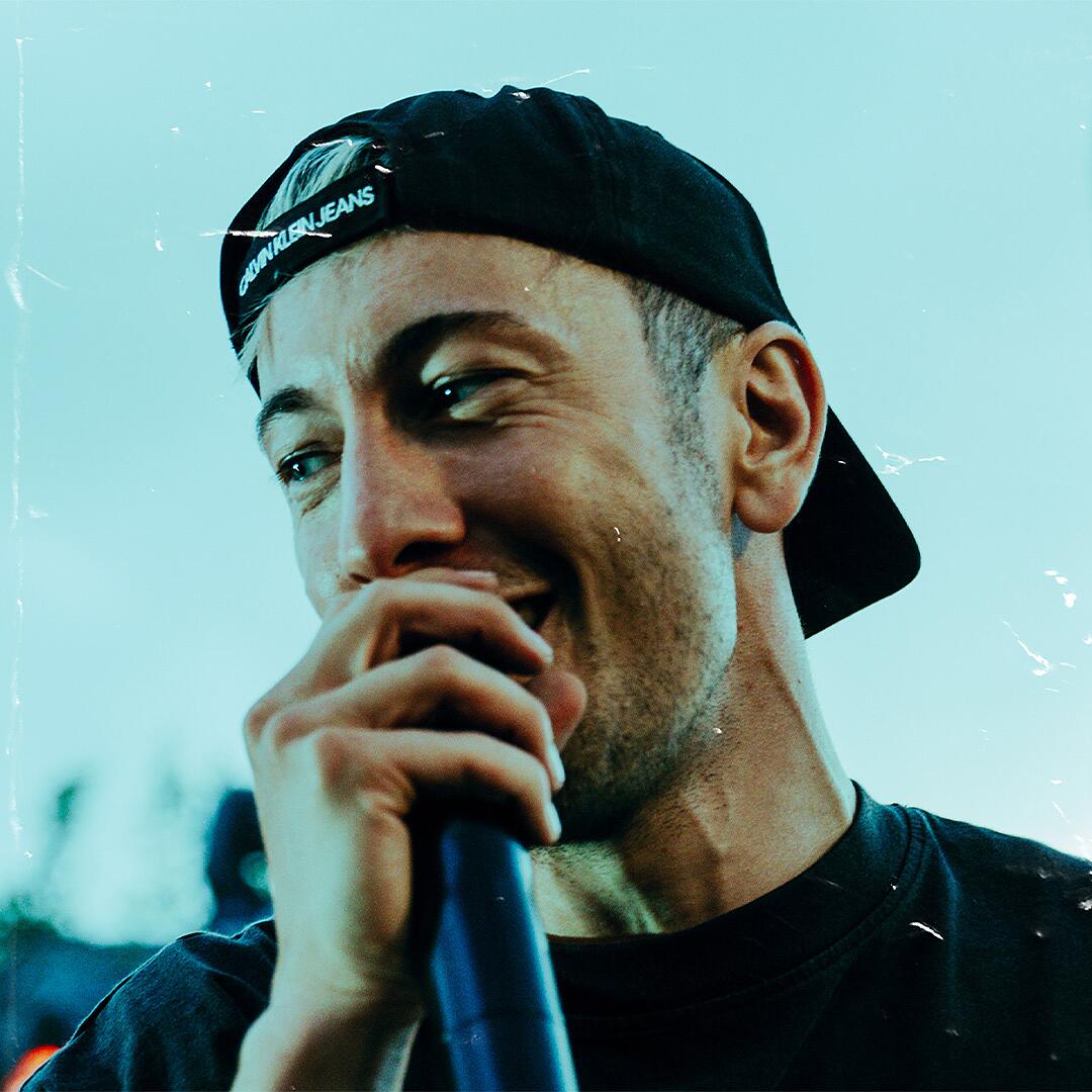 mace, rapper mit mikrofon und cap vor urbaner kulisse