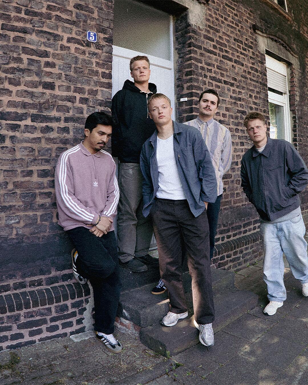 Bruchbude, fünfköpfige Band vor Backsteingebäude