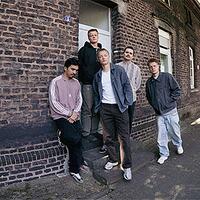 Bruchbude, fünfköpfige Band vor Backsteingebäude