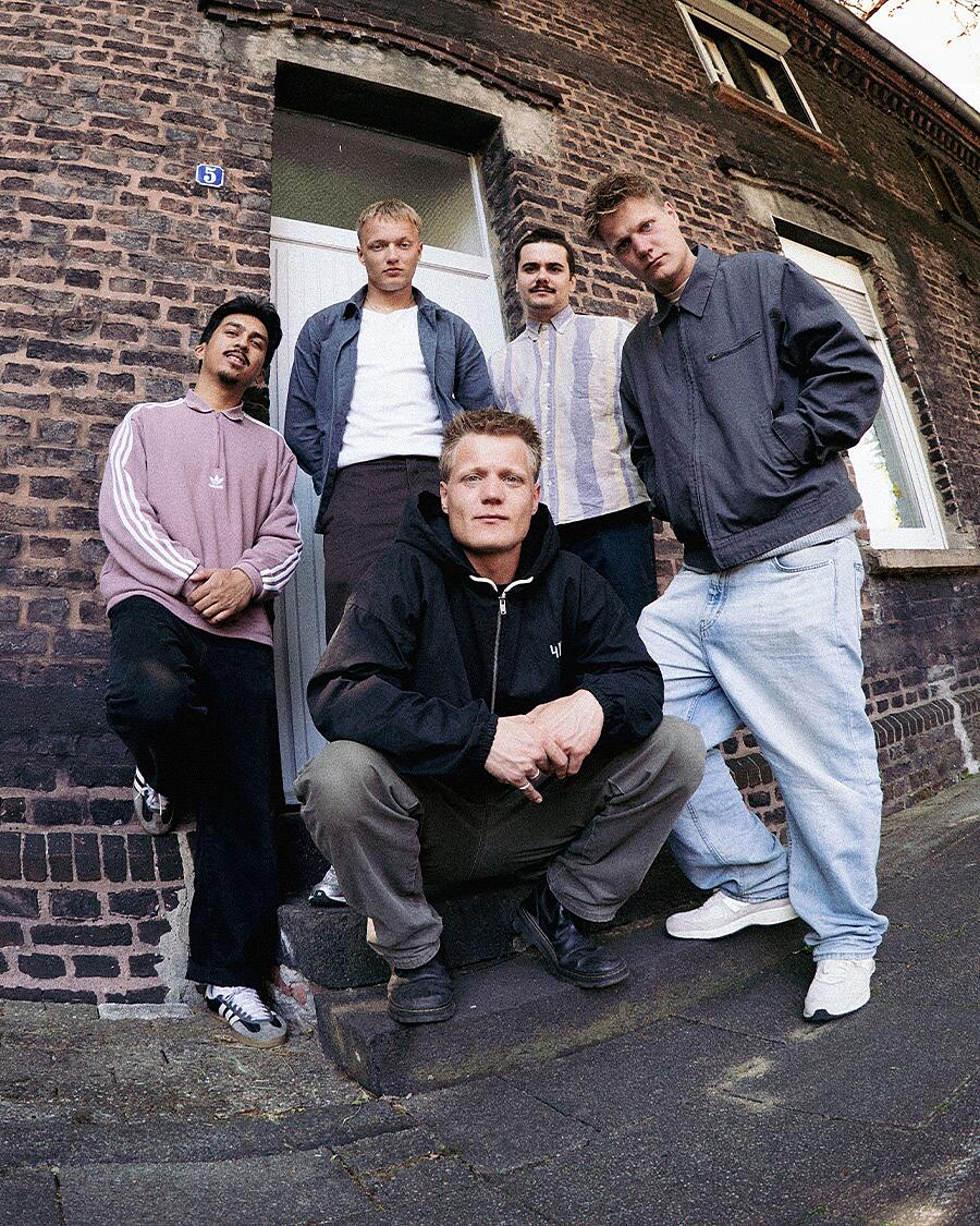 Bruchbude, fünfköpfige Band vor Backsteingebäude