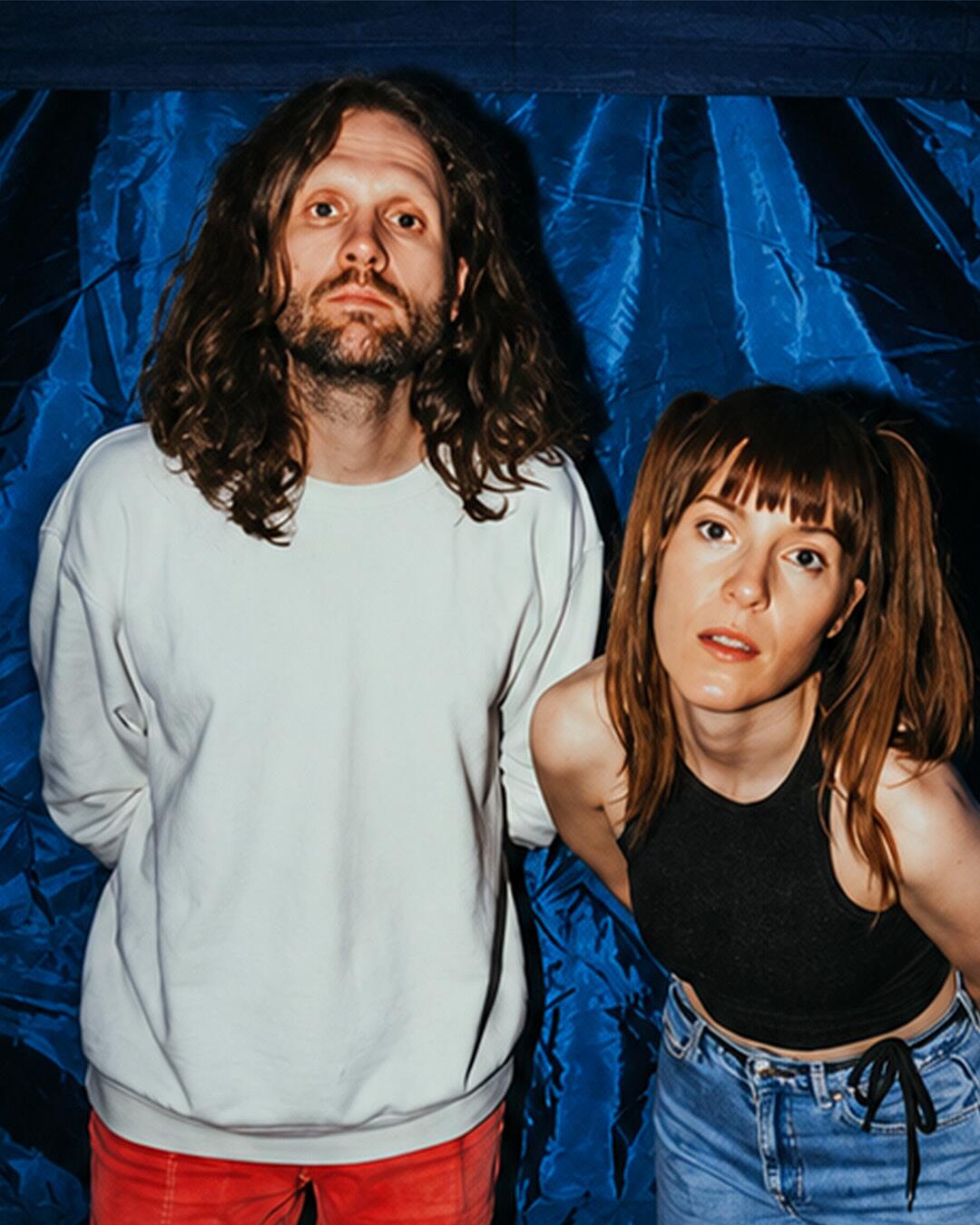 ell, duo vor blauem hintergrund mit direktem blick in kamera