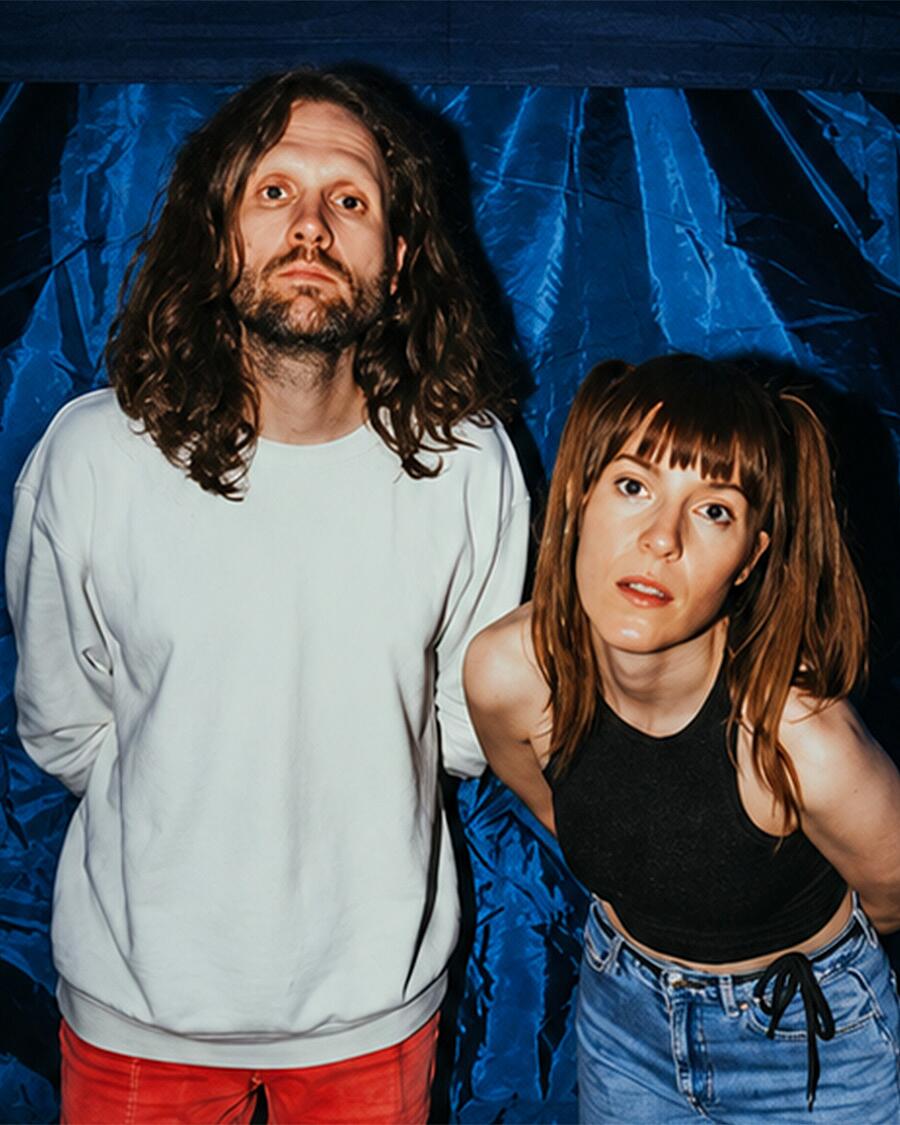 ell, duo vor blauem hintergrund mit direktem blick in kamera
